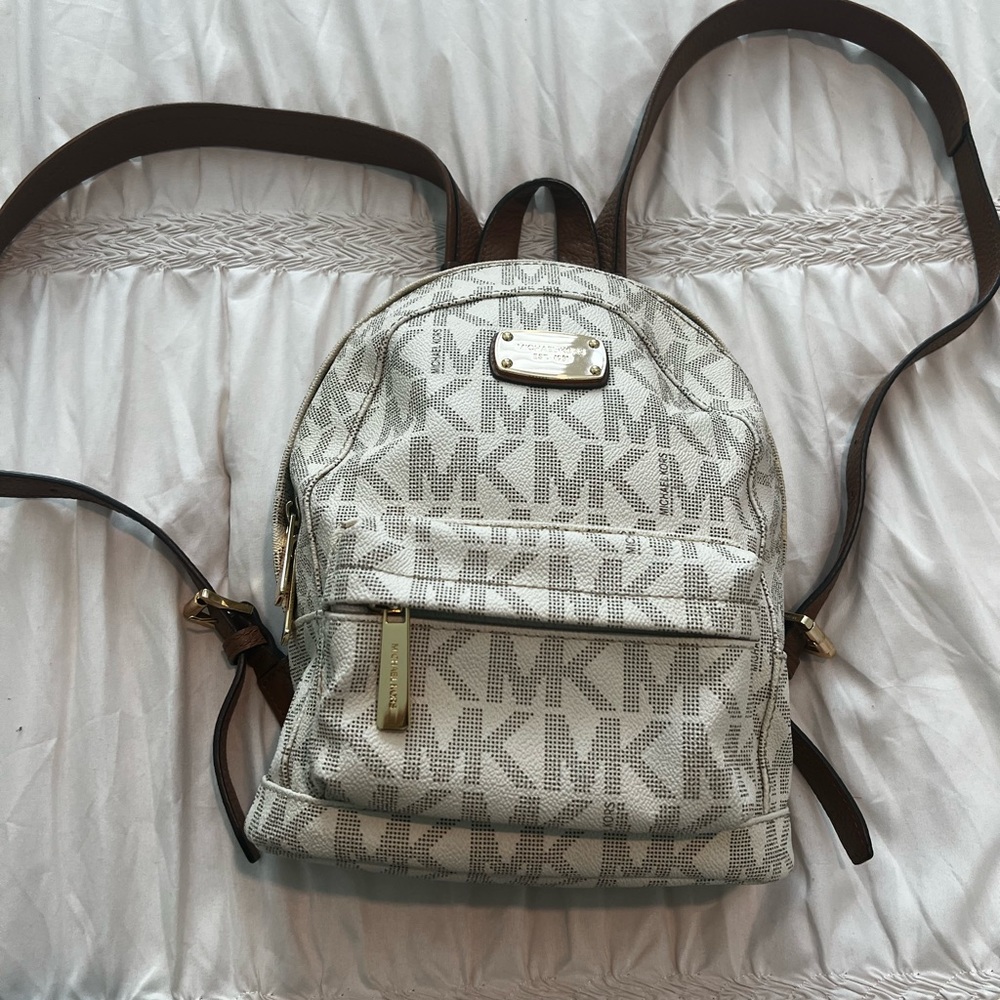 White leather Michael Kors Backpack with brown leather straps .